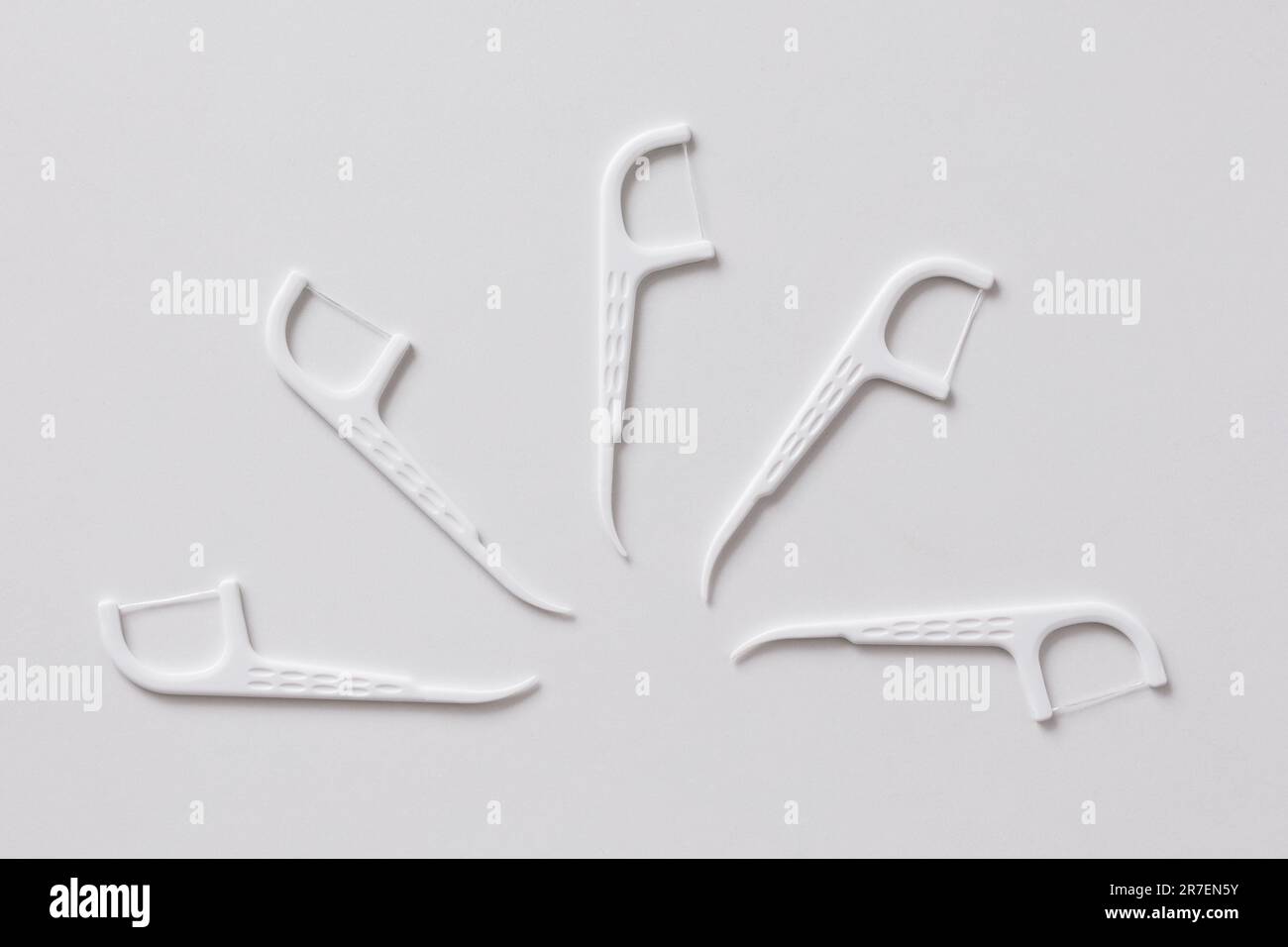 Many white dental toothpicks with dental floss on white background