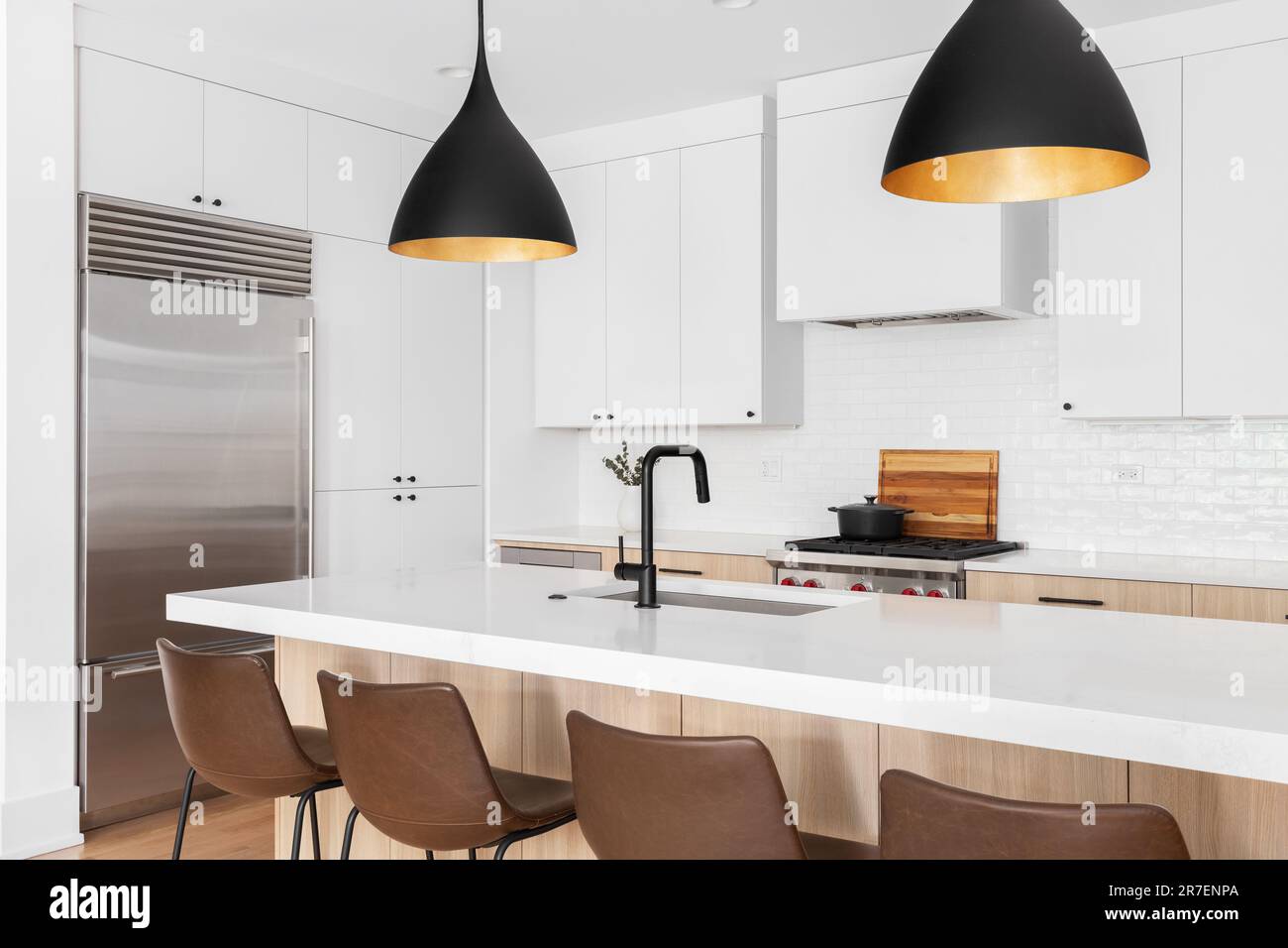 https://c8.alamy.com/comp/2R7ENPA/a-kitchen-detail-with-white-and-white-oak-cabinets-leather-chairs-sitting-at-an-island-and-a-black-and-gold-light-hanging-above-no-names-or-brands-2R7ENPA.jpg