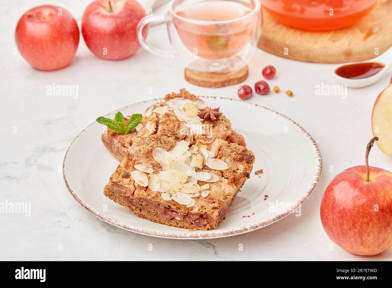 Glass tea pot with cranberry drink and apple pie dessert with apples and honey - autumn table setting Stock Photo