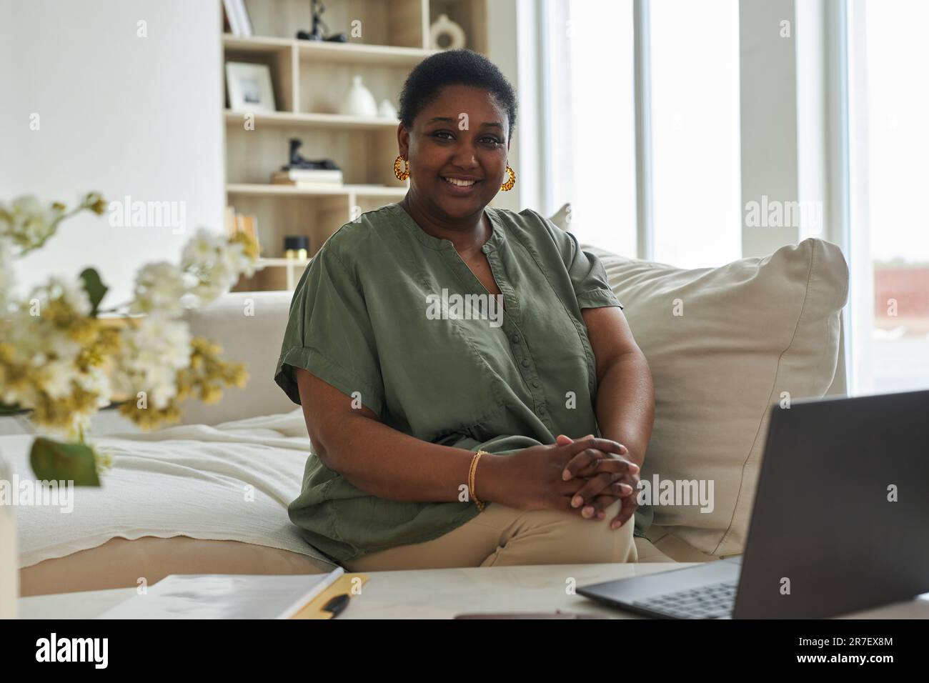 Portrait of African American woman smiling at camera while working on laptop at home Stock Photo