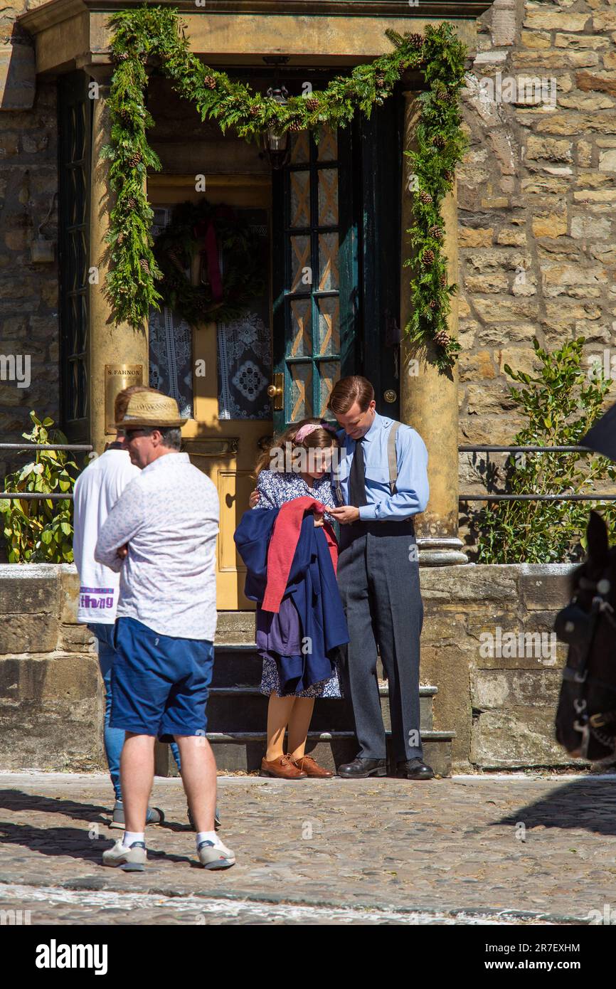 Grassington, Yorkshire Dales, UK 14th June 2023. Cast and crew of the popular Channel 5 and PBS re-make of All Creatures Great and Small were out in force filming for the series 4 Christmas special.  Rachel Shenton (Helen Herriot) and Nicolas Ralph (James Herriot) rehearse a scene on the steps of Skeldale House before screnes are brought in to the block the view for the public. Credit: Tom Holmes / Alamy Live News Stock Photo