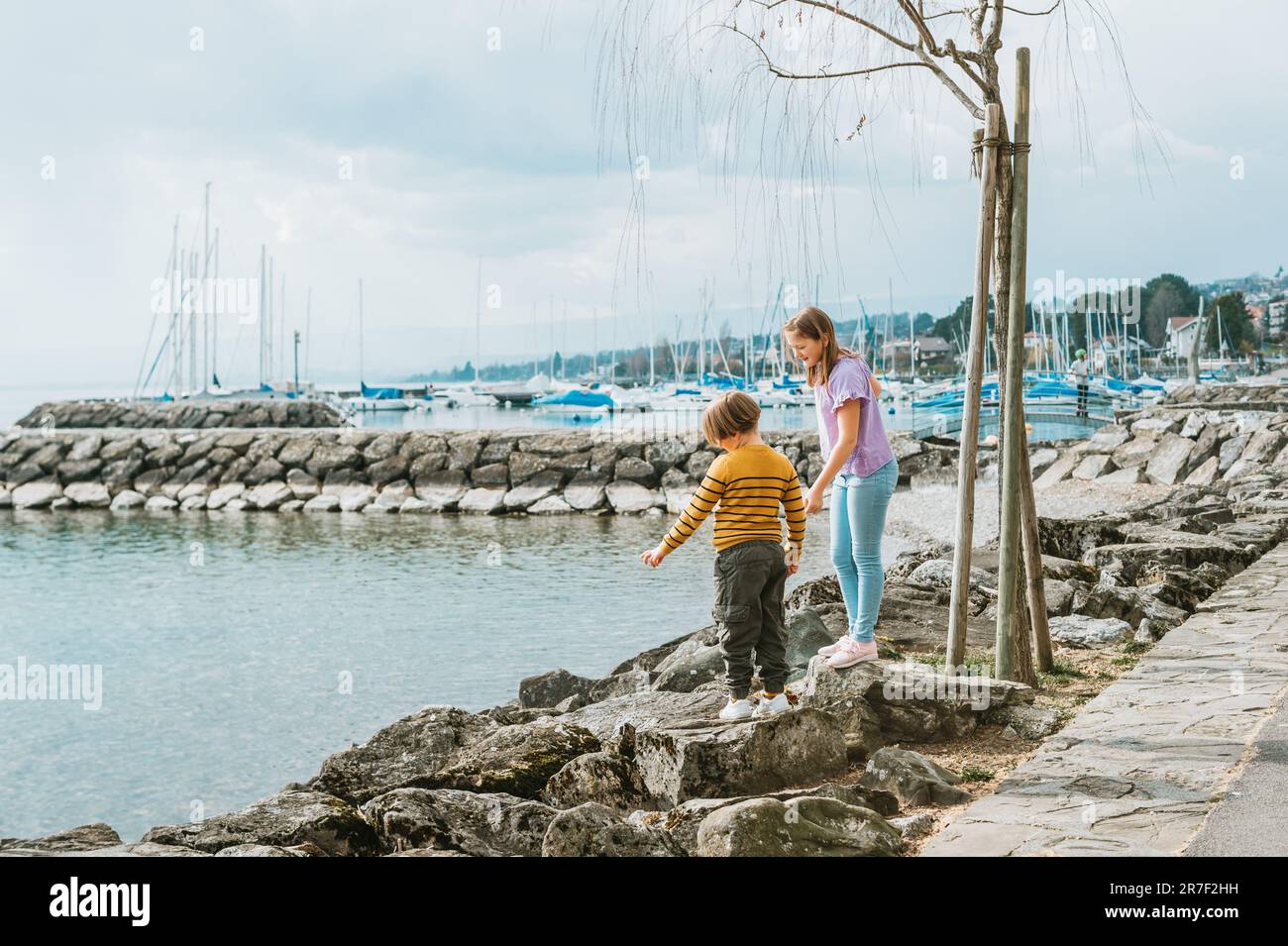 Two funny kids, little brother and sister, playing together outside by the lake Stock Photo Alamy