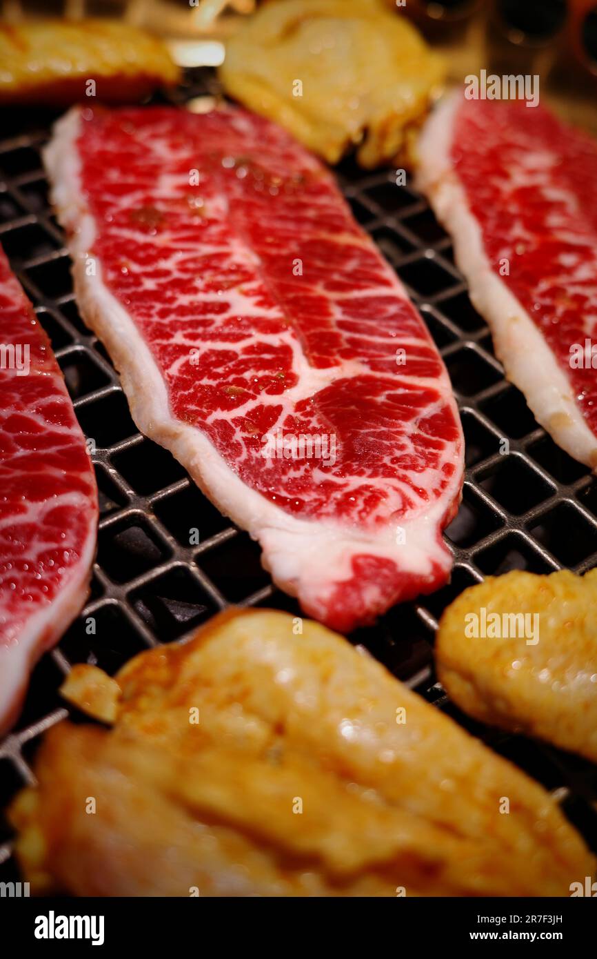 A close-up image of a variety of barbecued meats, fish and vegetables sizzling on a hot grill Stock Photo