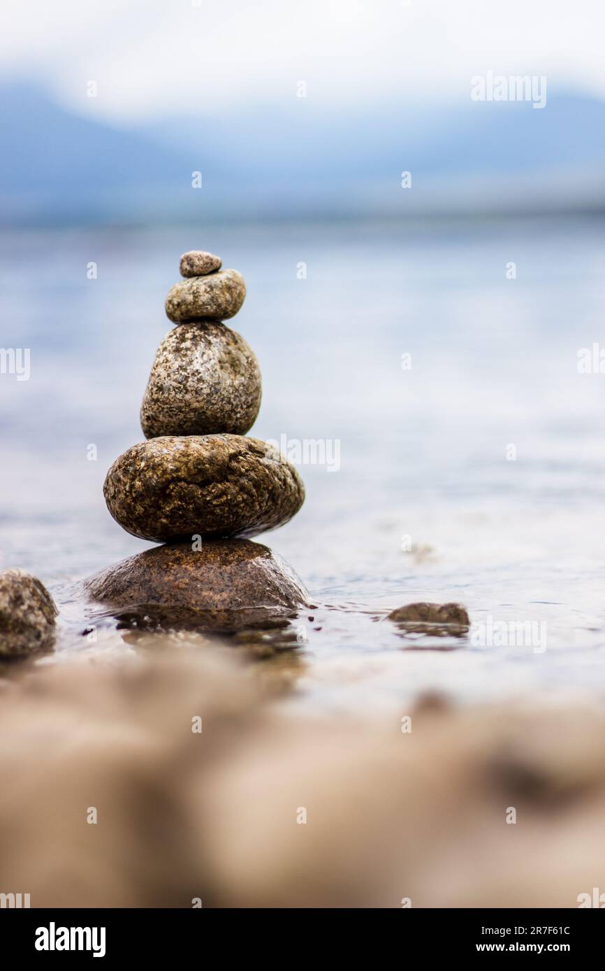 A formation of balanced rocks situated on a beach near a body of water ...