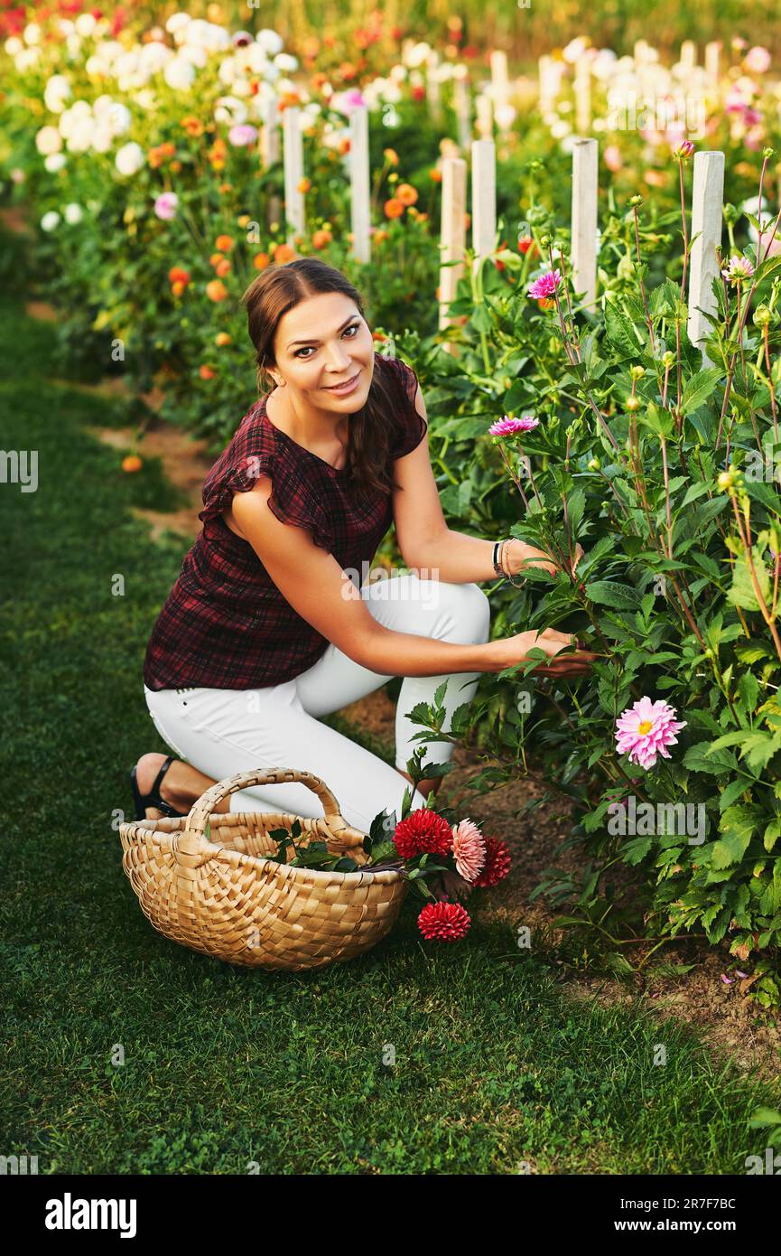 Outdoor portrait of beautiful woman cutting flowers, flower farm