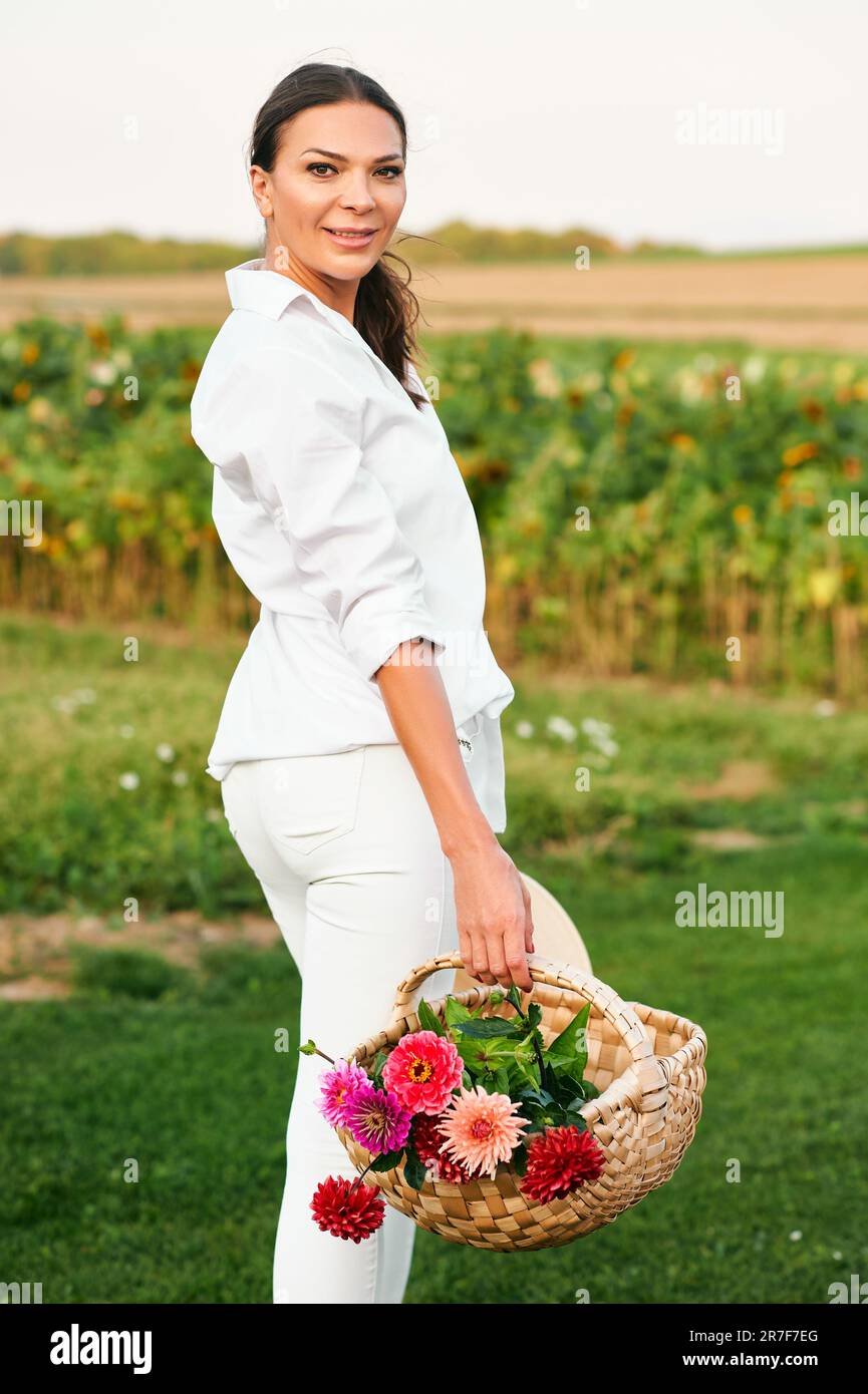 Outdoor portrait of beautiful woman posing in garden, holding basket ...
