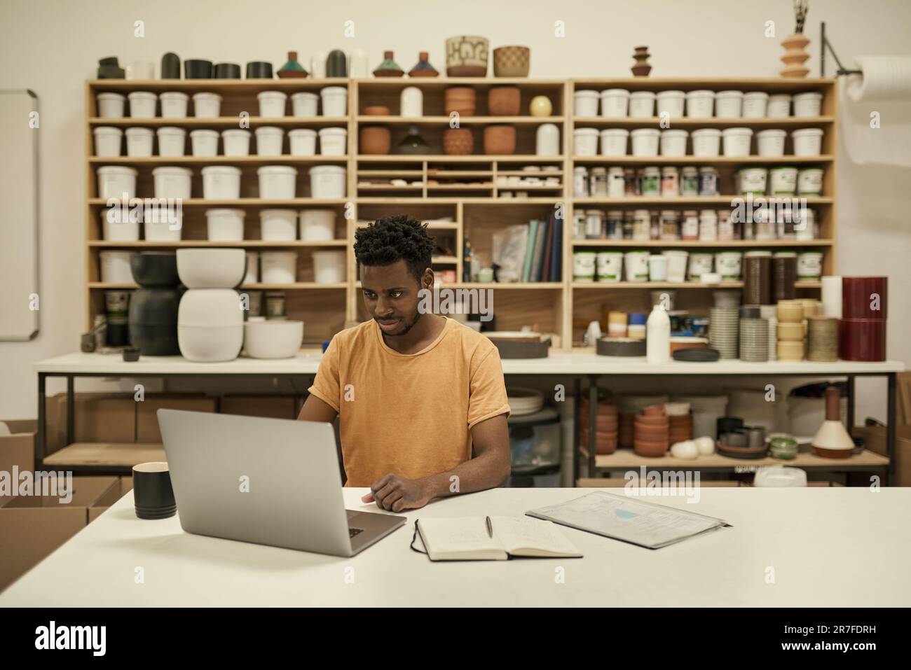 African ceramics workshop manager using a laptop in a studio Stock Photo