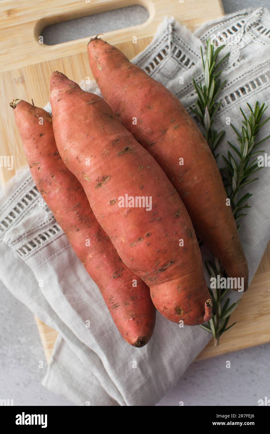 Raw sweet potatoes on cutting board. . Orange kumara, yam. Healthy