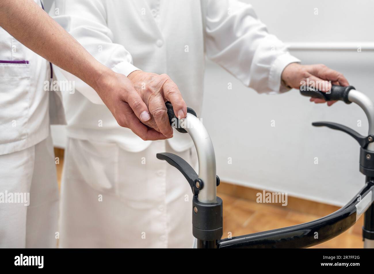 Nurse assists her senior patient on folding walker. Recuperation for elderly, seniors care, nursing home. High quality photo Stock Photo