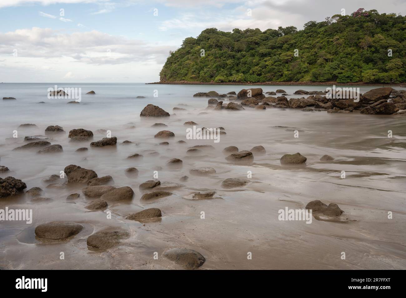 Rocks in silky sea water. Many brown stones on sea shore Stock Photo