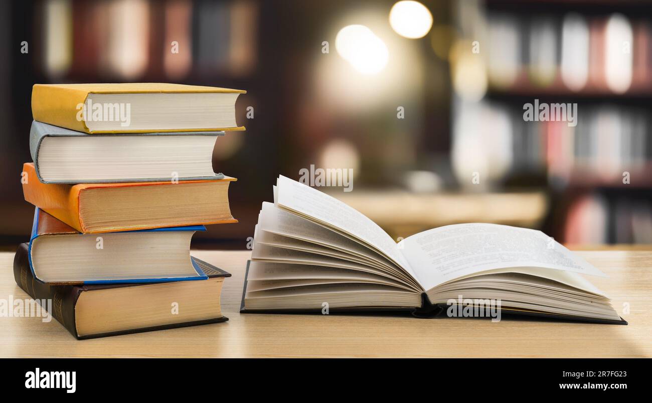 Book stack and open book on the desk in public library Stock Photo - Alamy