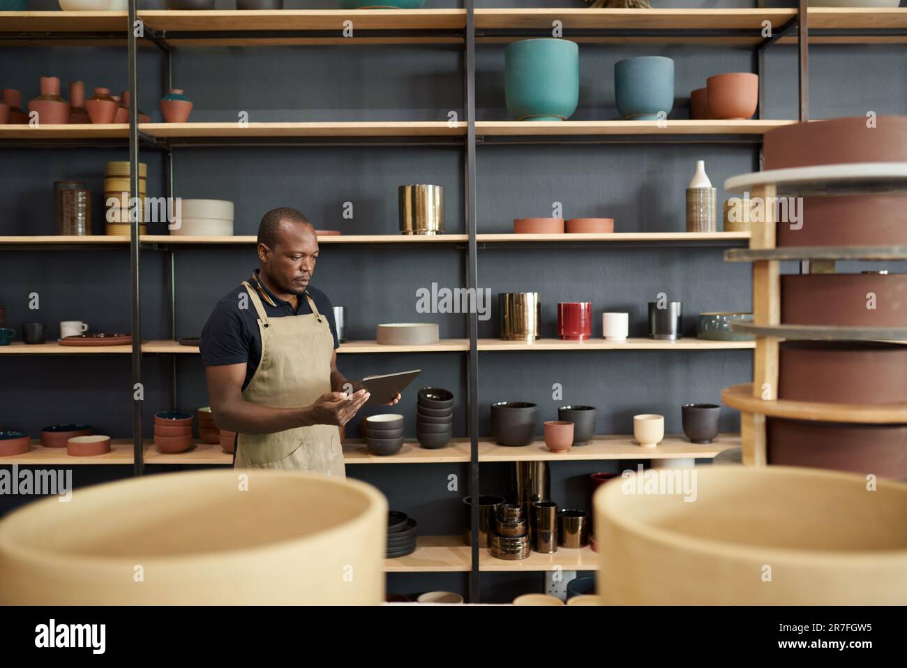 African ceramist using a digital tablet in a pottery workshop Stock Photo