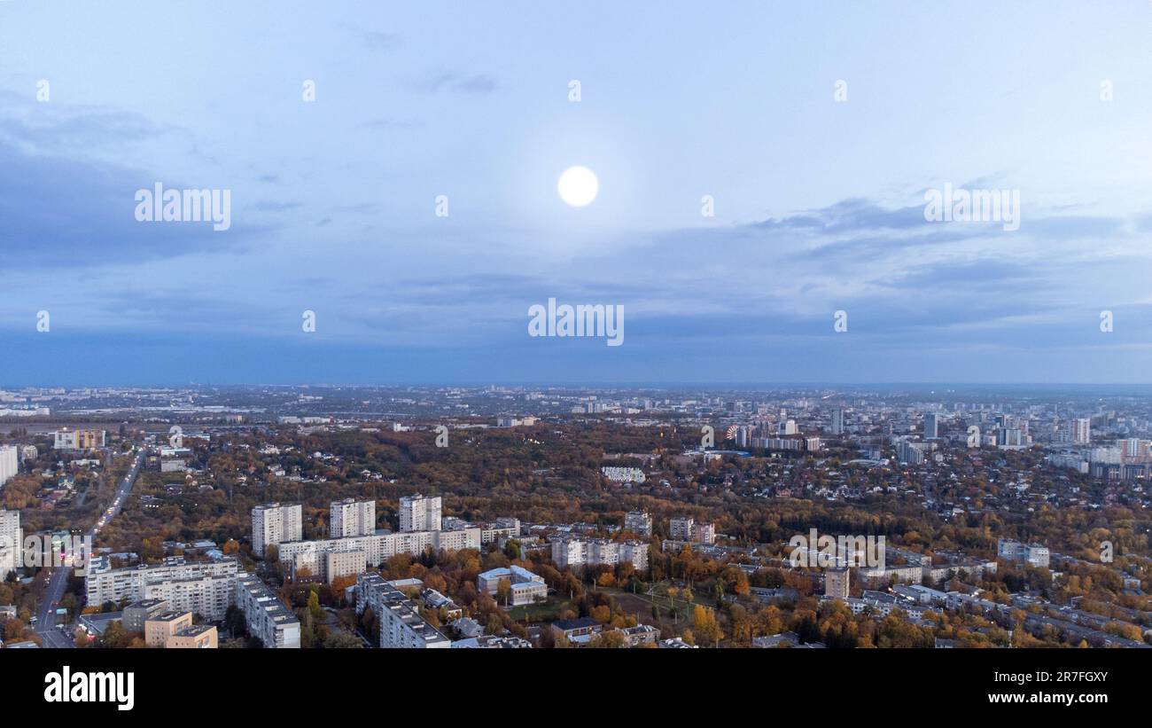 Aerial autumn evening city view with big white moon. Residential district with park and scenic cloudy sky. Kharkiv, Ukraine Stock Photo
