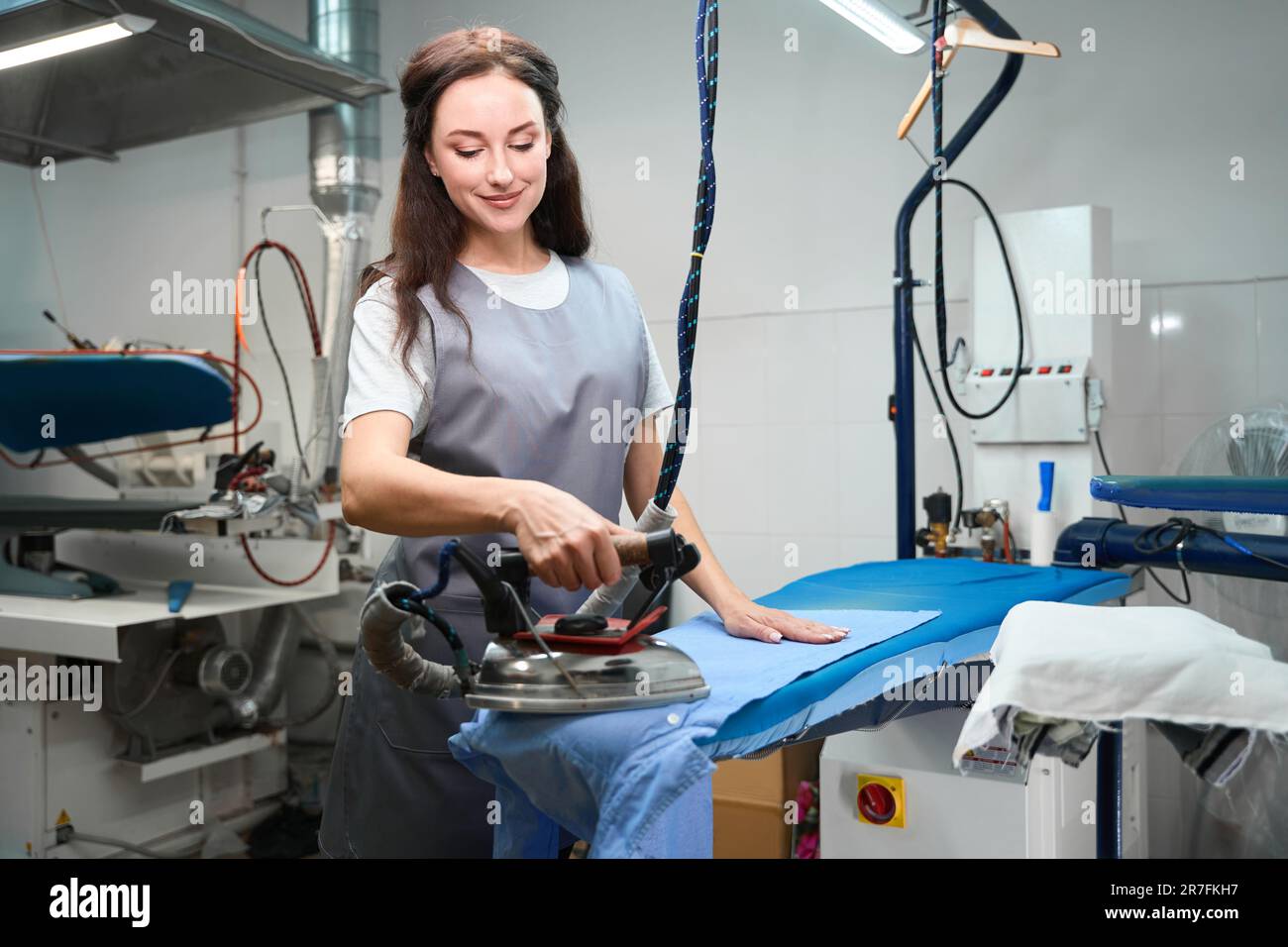 Laundry operator ironing clothes to get rid of wrinkles on shirt Stock