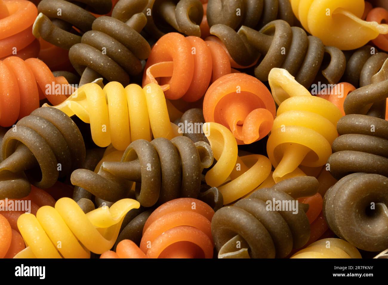 Uncooked Trottole tricolore pasta close up full frame as background Stock Photo