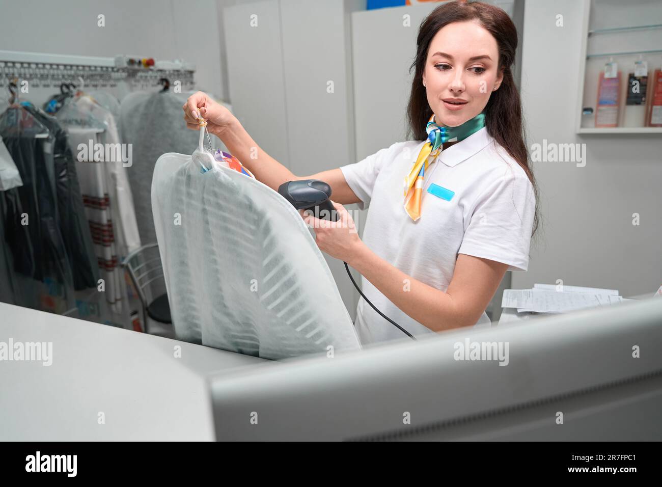 Administrator of drycleaning office scanning barcode on tag on garment