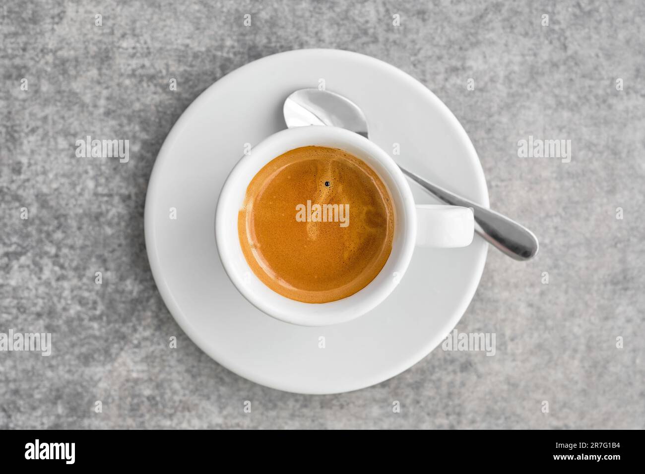 White cup with fragrant strong espresso coffee with thick foam in a traditional Greek coffee shop. Top view of coffee with saucer on gray marble table Stock Photo
