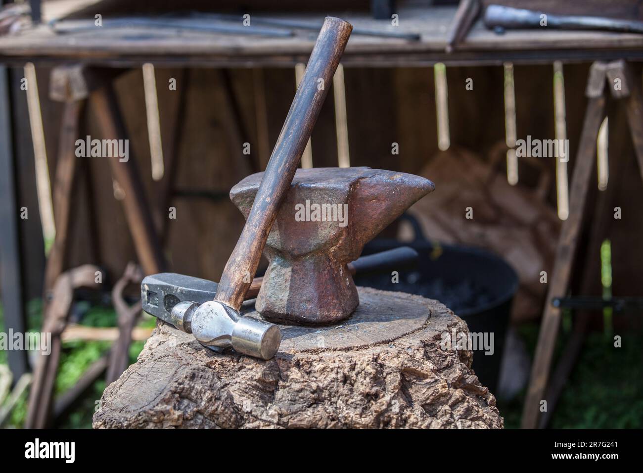 Anvil, hammer and mace displayed over cork oak stump. Blacksmith tools from a ancient roman military camp. Stock Photo