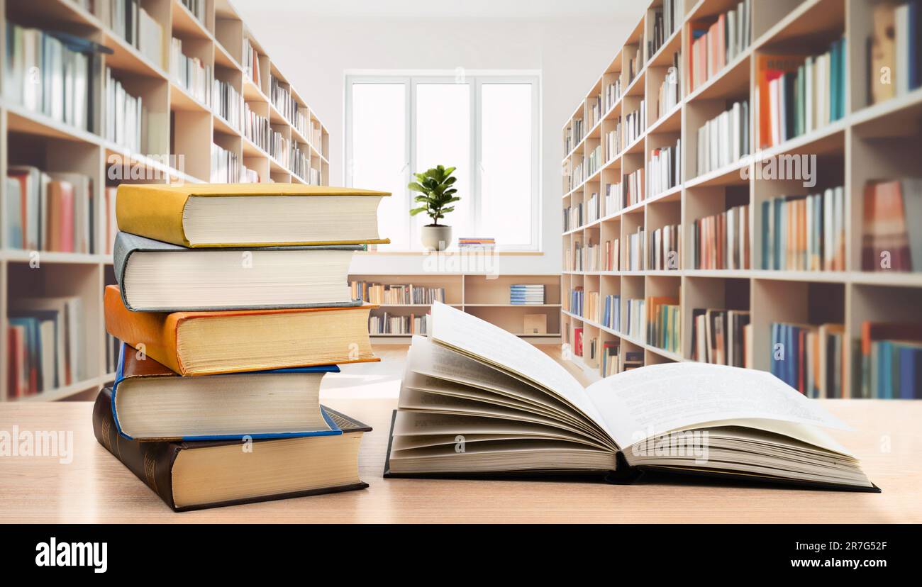 Book stack and open book on the desk in modern public library Stock