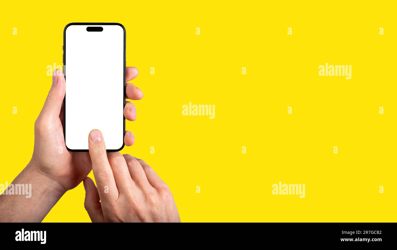 Lodz, Poland May 30 2023 Hand holding mobile phone, finger clicking on blank screen mock-up, tapping ok on display on yellow ad banner. Stock Photo