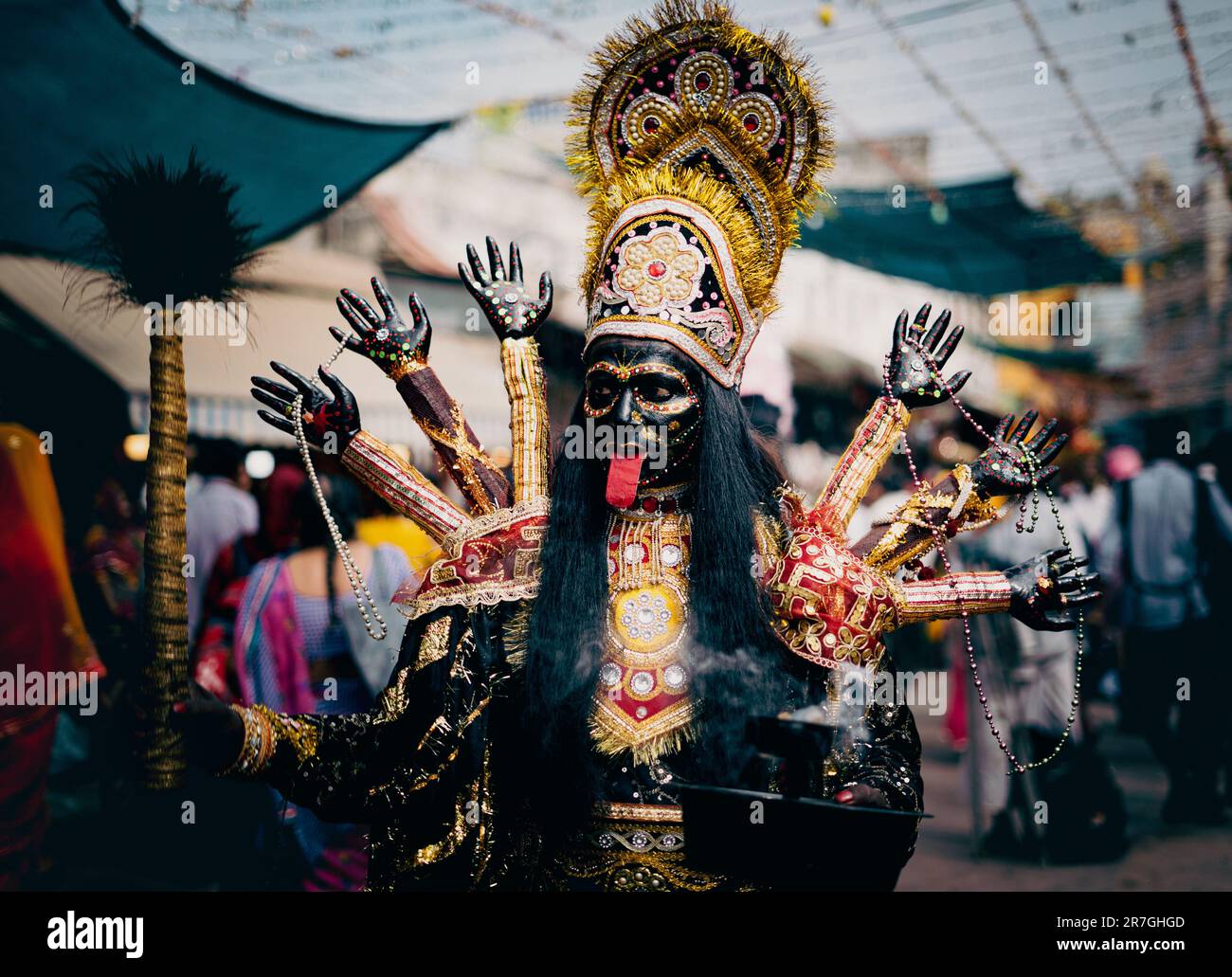 A man wearing a black and gold ensemble stands amongst a group of people Stock Photo
