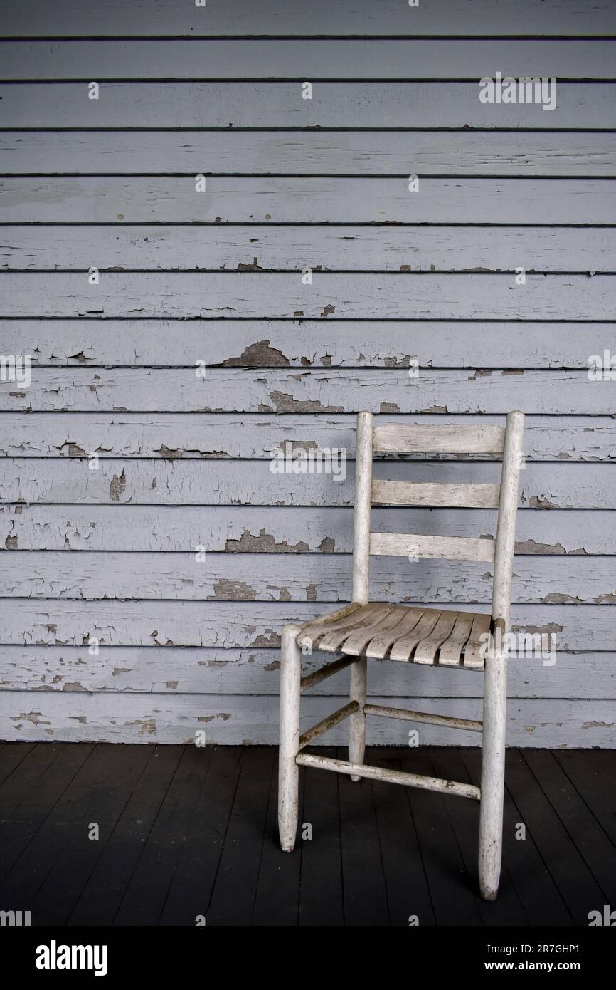 Dirty wooden chair on wrap around front porch Stock Photo