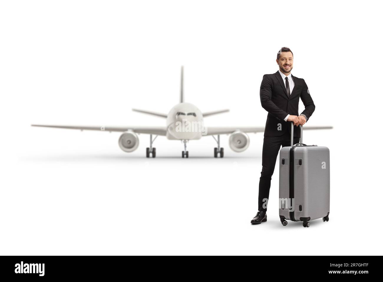 Full length portrait of a professional man posing with a suitcase in front of an airplane isolated on white background Stock Photo