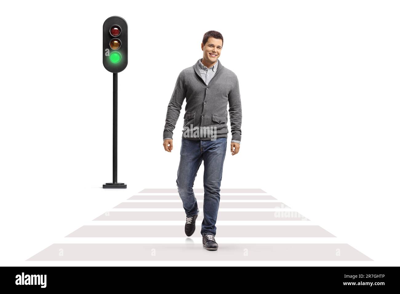 Full length portrait of a young smiling man walking at a pedestrian crossing isolated on white background Stock Photo