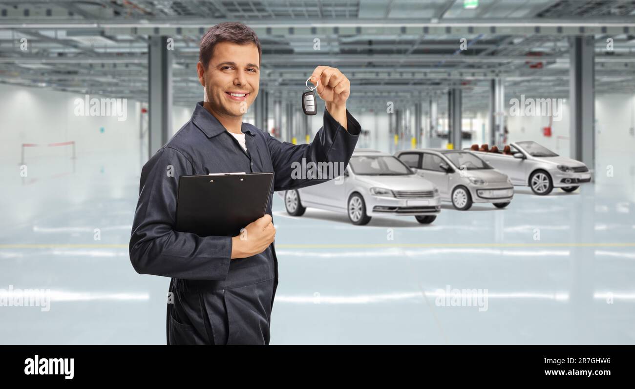 Auto mechanic holding a clipboard and car keys inside a garage with cars Stock Photo Alamy