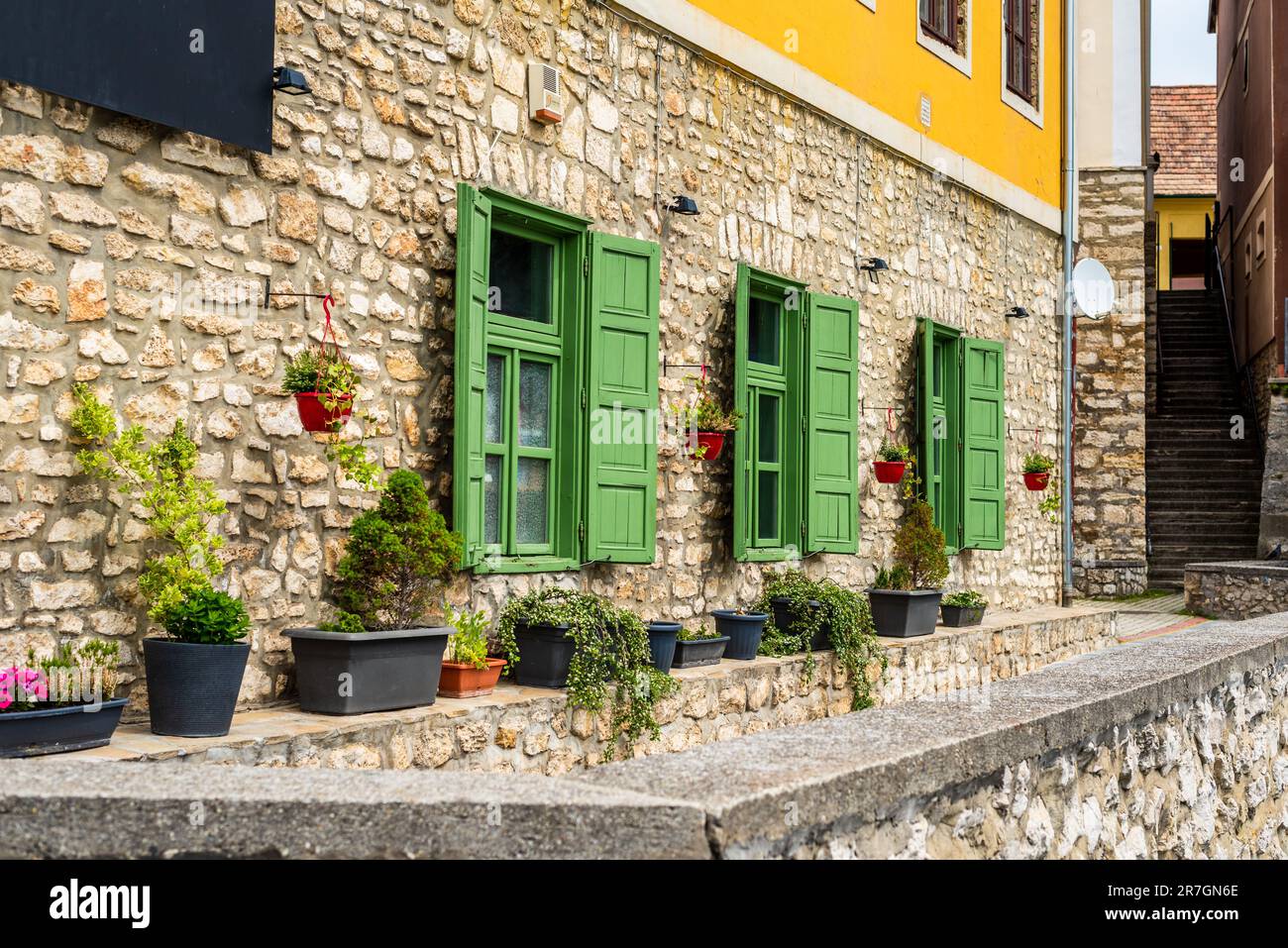 Beautiful green jalousie windows of renovated old building with stone walls. Stock Photo