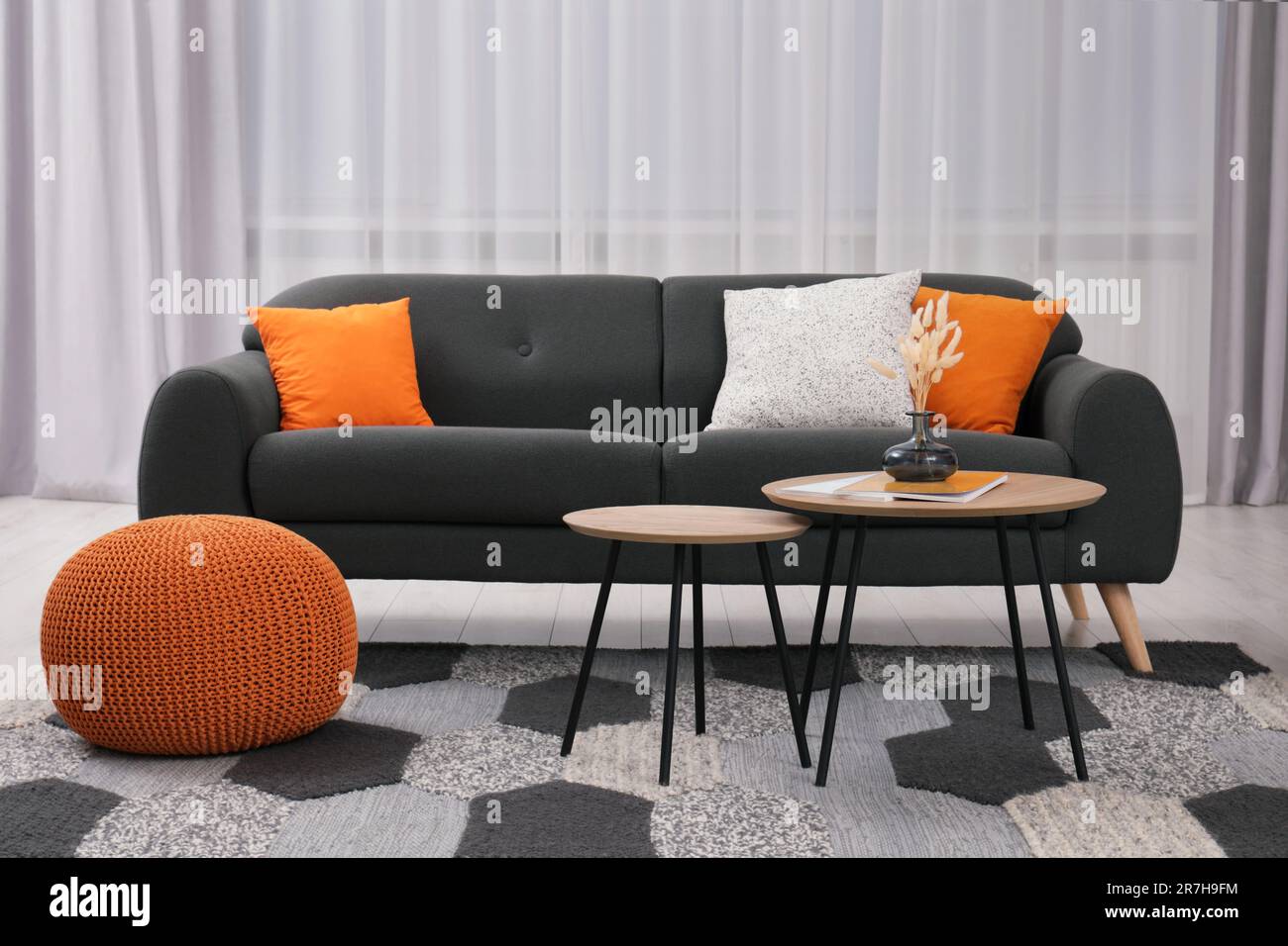 Comfortable sofa, pouf and coffee table in stylish room. Interior