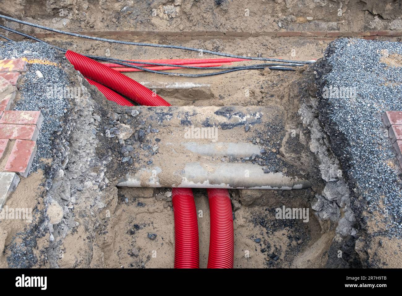 Electric cables in red corrugated pipe are buried underground on the