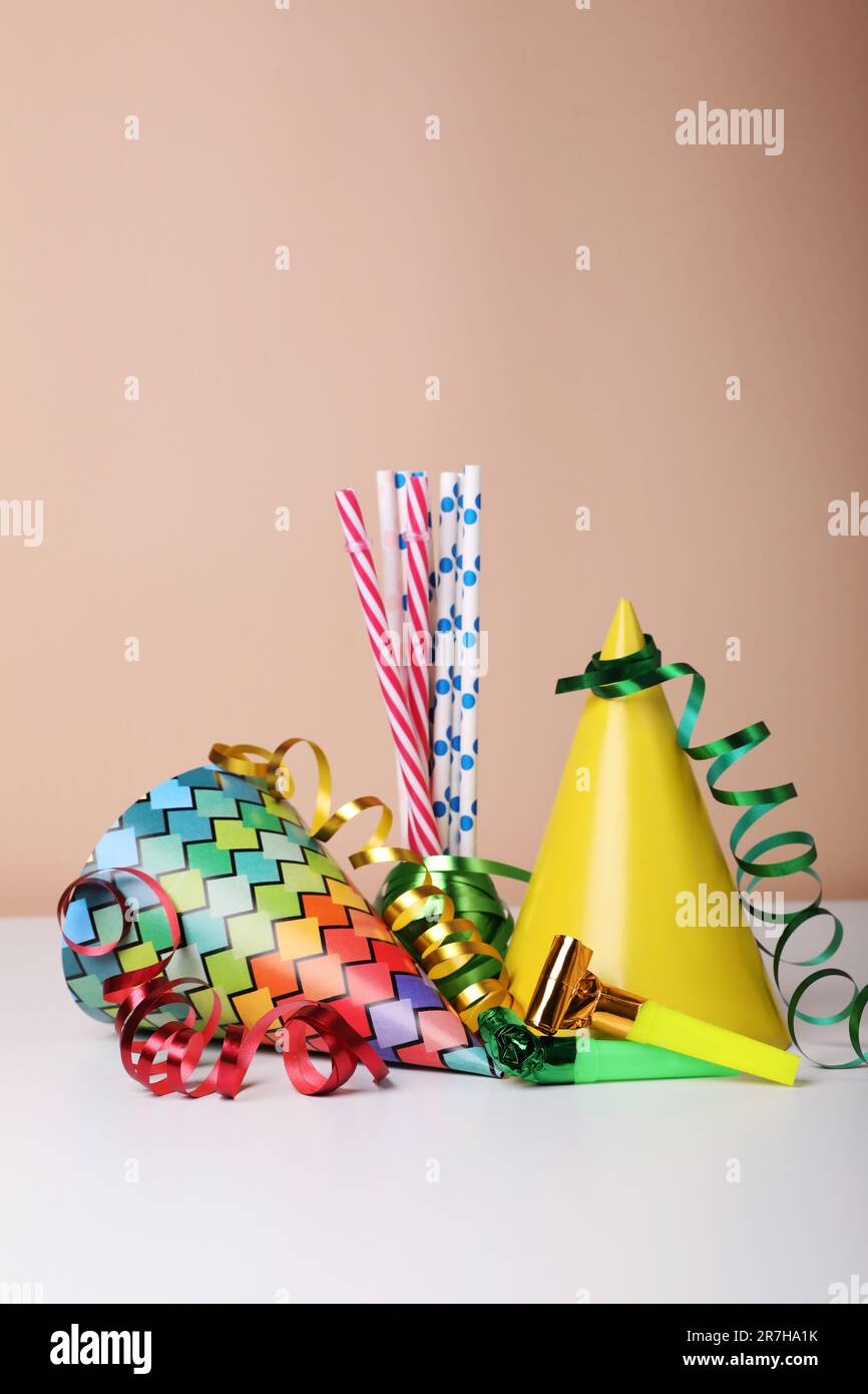 Colorful party hats, streamers and straws on white table. Birthday