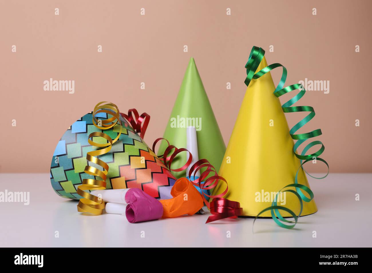 Colorful party hats, streamers and blowers on white table. Birthday