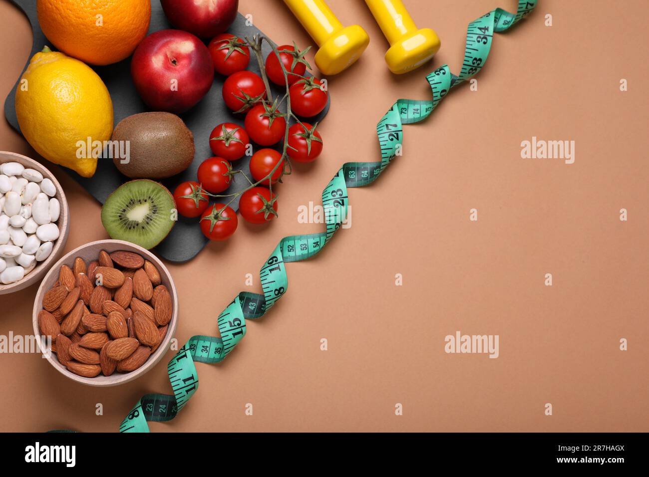 Measuring tape, almonds, fresh fruits and tomatoes on light brown