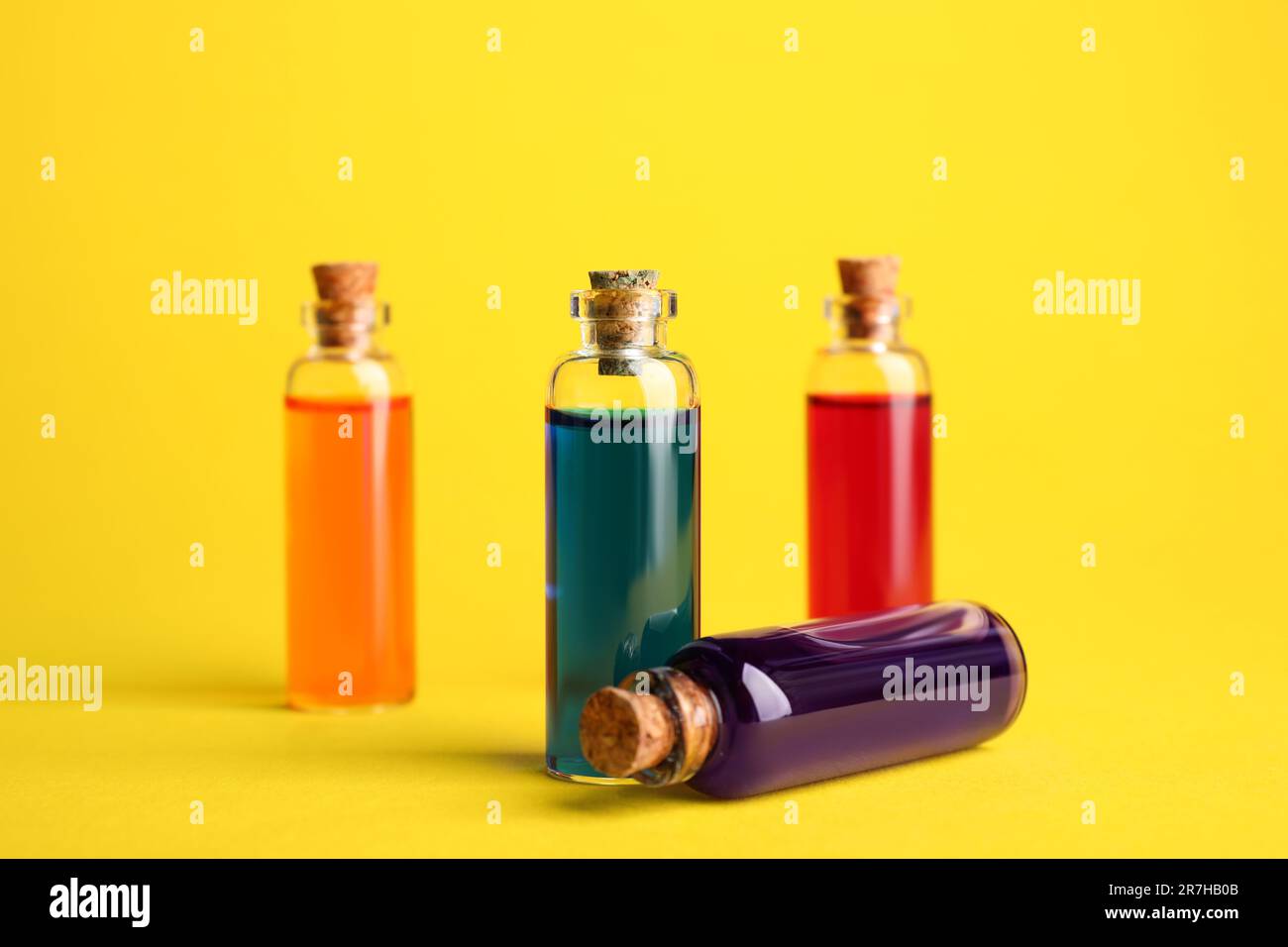 Bottles with different food coloring on yellow background Stock Photo