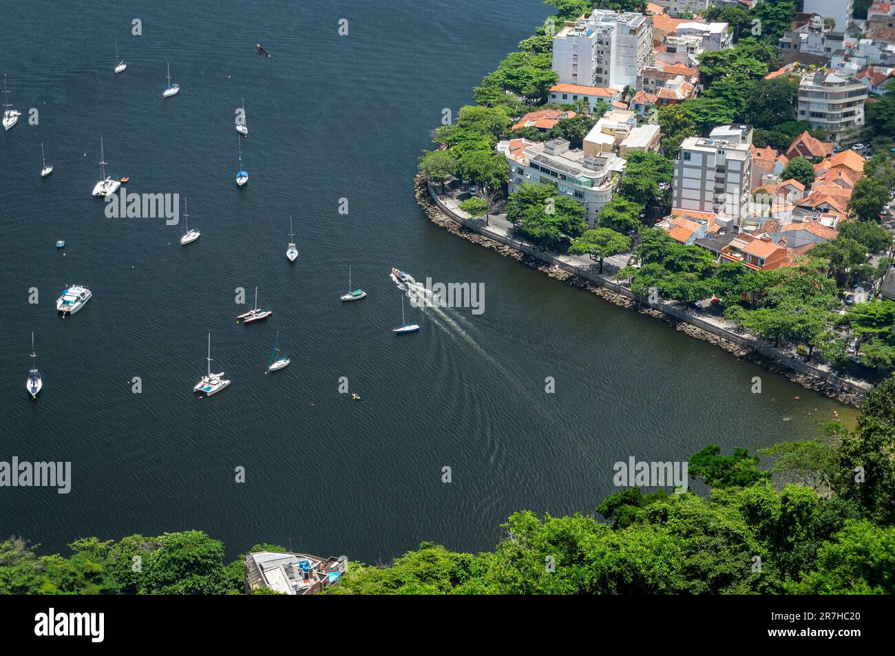 Partial view of Guanabara bay waters with some boats nearby Urca short wall and residential area buildings of Urca district in a summer sunny day. Stock Photo