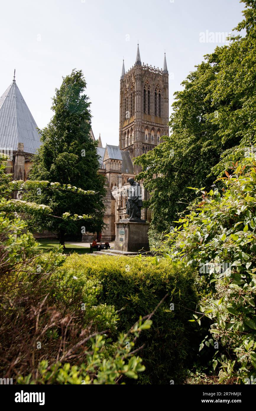 The statue of Alfred Lord Tennyson sitting on Lincoln Cathedral Green a Grade II listed statue, dating from 1905, by G F Watts, RA and restored in 1970. It is a bronze standing figure with a dog, on an ashlar pedestal with plaques to the east and west. Stock Photo