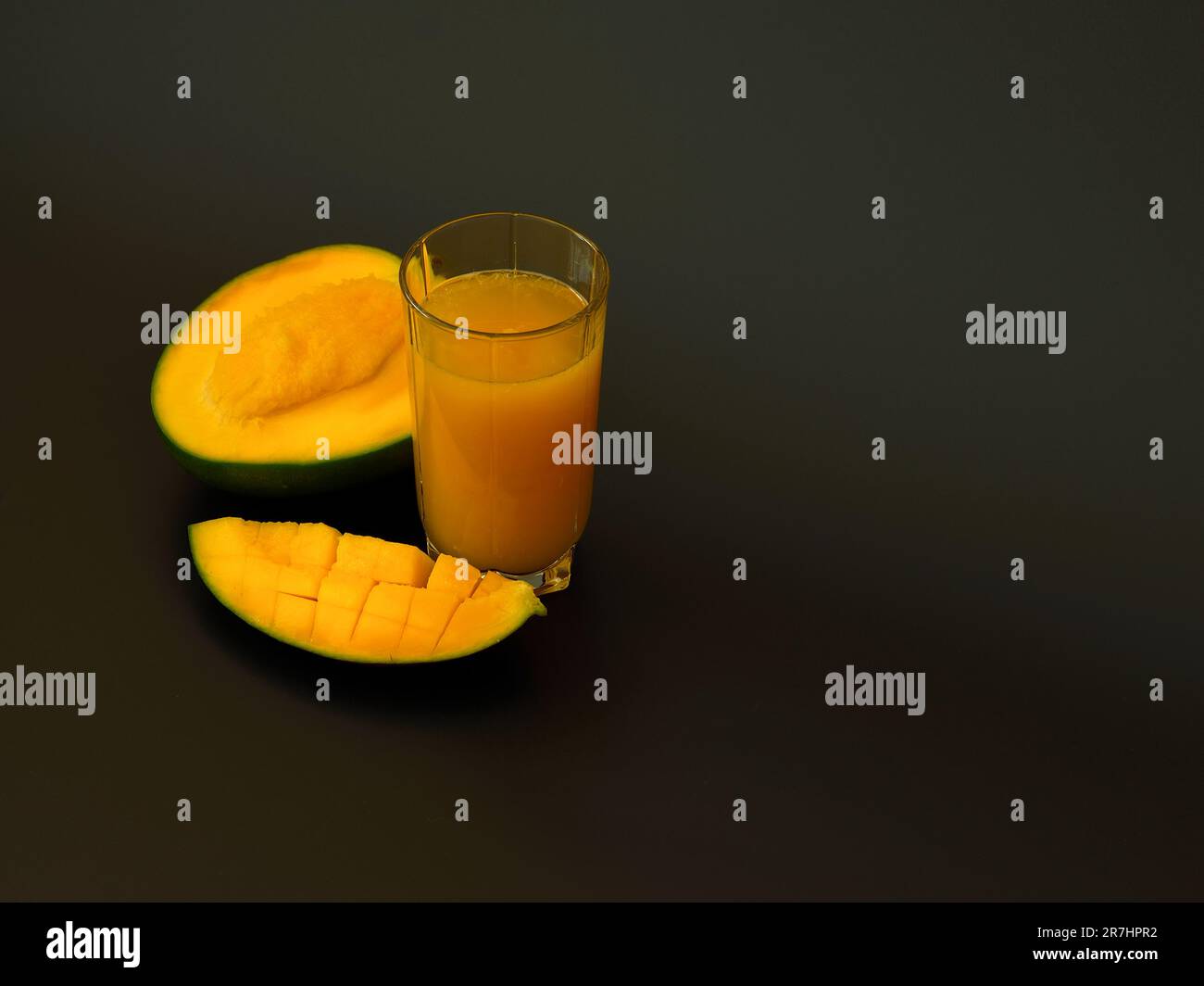 https://c8.alamy.com/comp/2R7HPR2/mango-juice-in-a-tall-glass-on-a-black-background-next-to-pieces-of-ripe-exotic-fruit-close-up-2R7HPR2.jpg
