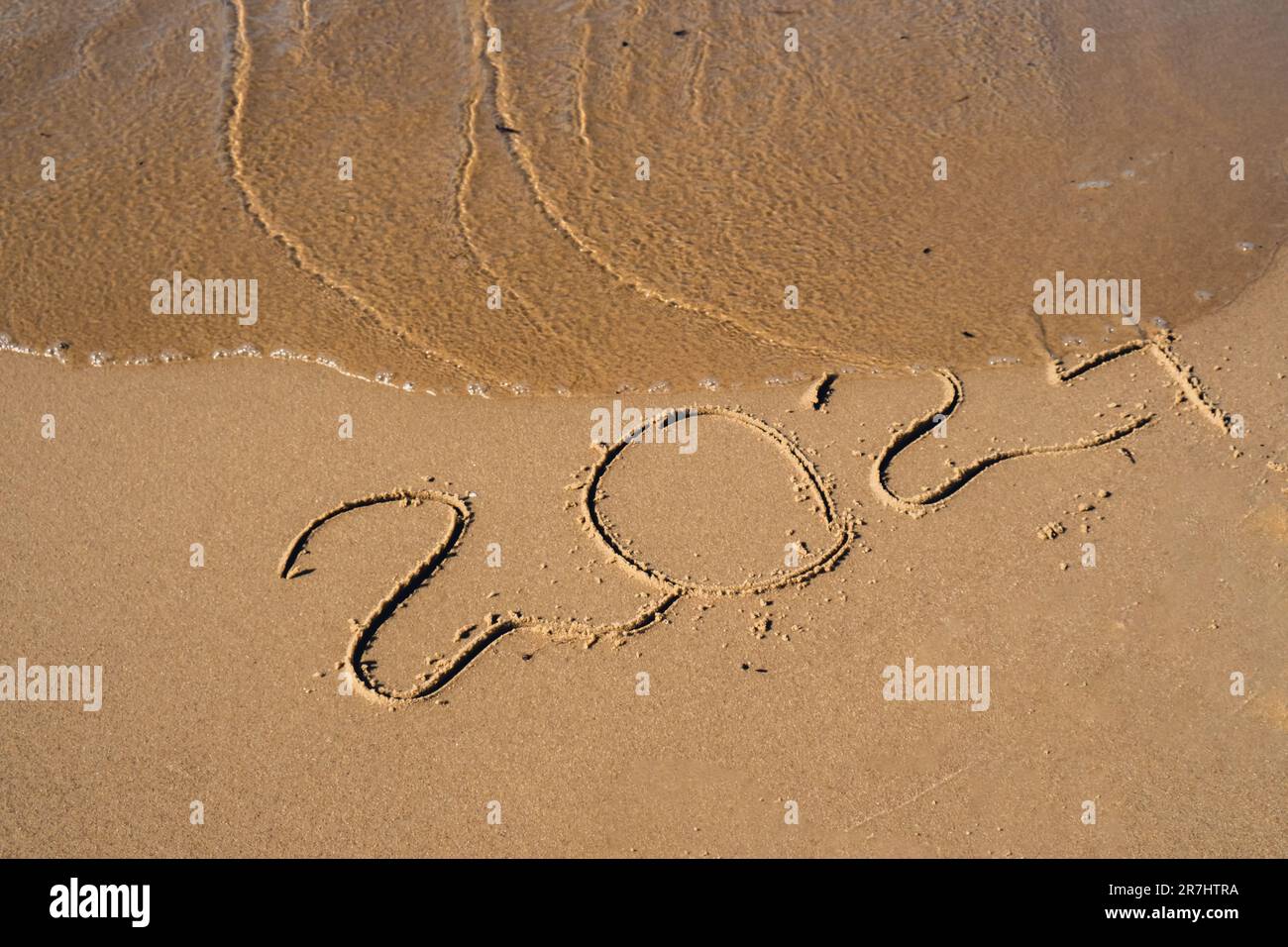 New Year concept. Text 2024 handwritten in sand surface. Blue 