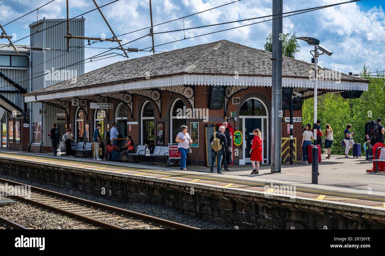 Train Station, Grantham, Lincolnshire, UK – Passengers and people travelling waiting for a train at the railway station on a sunny summer afternoon Stock Photo