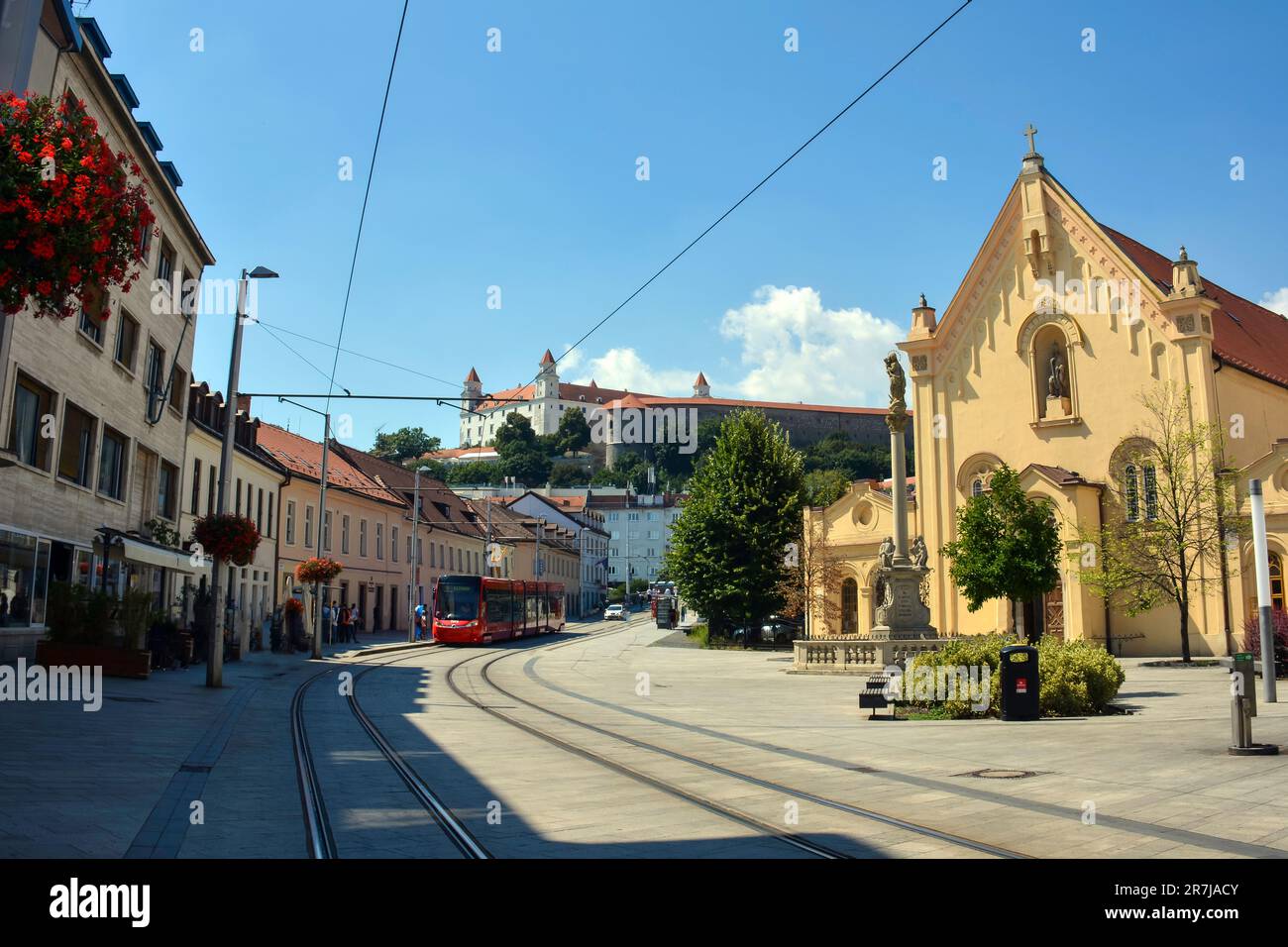 Colorful Streets of Bratislava Old Town, with the St. Stephan Capuchin Church, the Tramway and the Castle in the Background Stock Photo