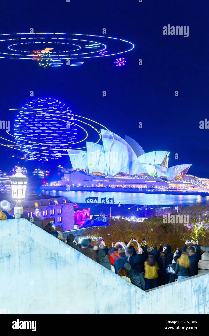 Crowds gather to witness the 'Written in the Stars' light show and drone display at the 2023 'Vivid Sydney' Festival in Australia. The show featured h Stock Photo