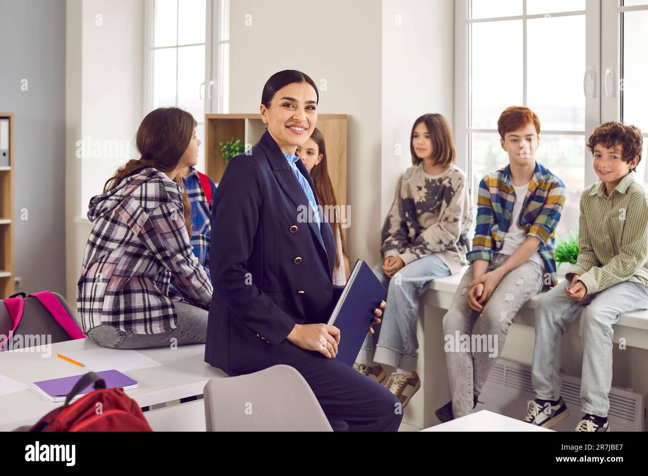 Smiling female teacher standing with her students in classroom Stock ...