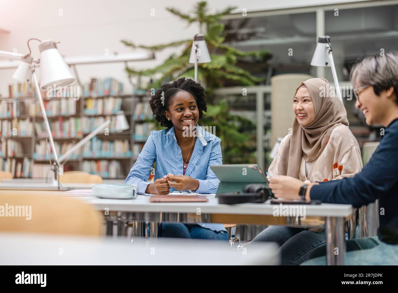 Multiethnic group of students sitting in a library and studying ...
