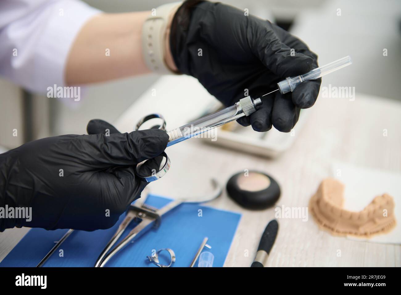 Closeup dentist's hands recharging cartridge with anesthetic in