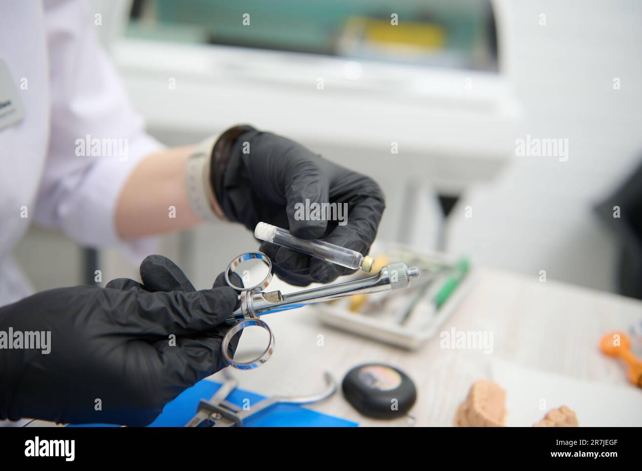Closeup dentist hands placing a cartridge with dental anesthesia in