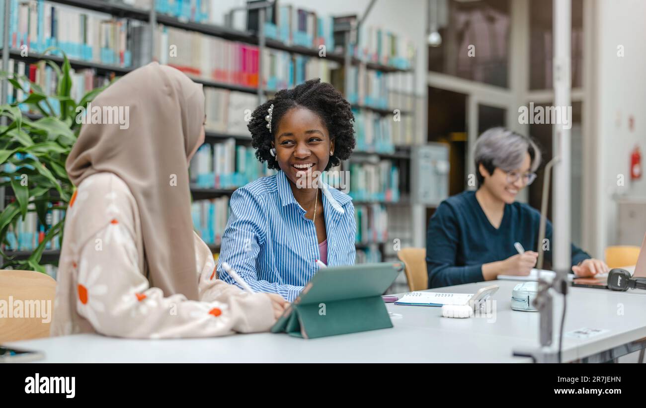 Multiethnic group of students sitting in a library and studying ...