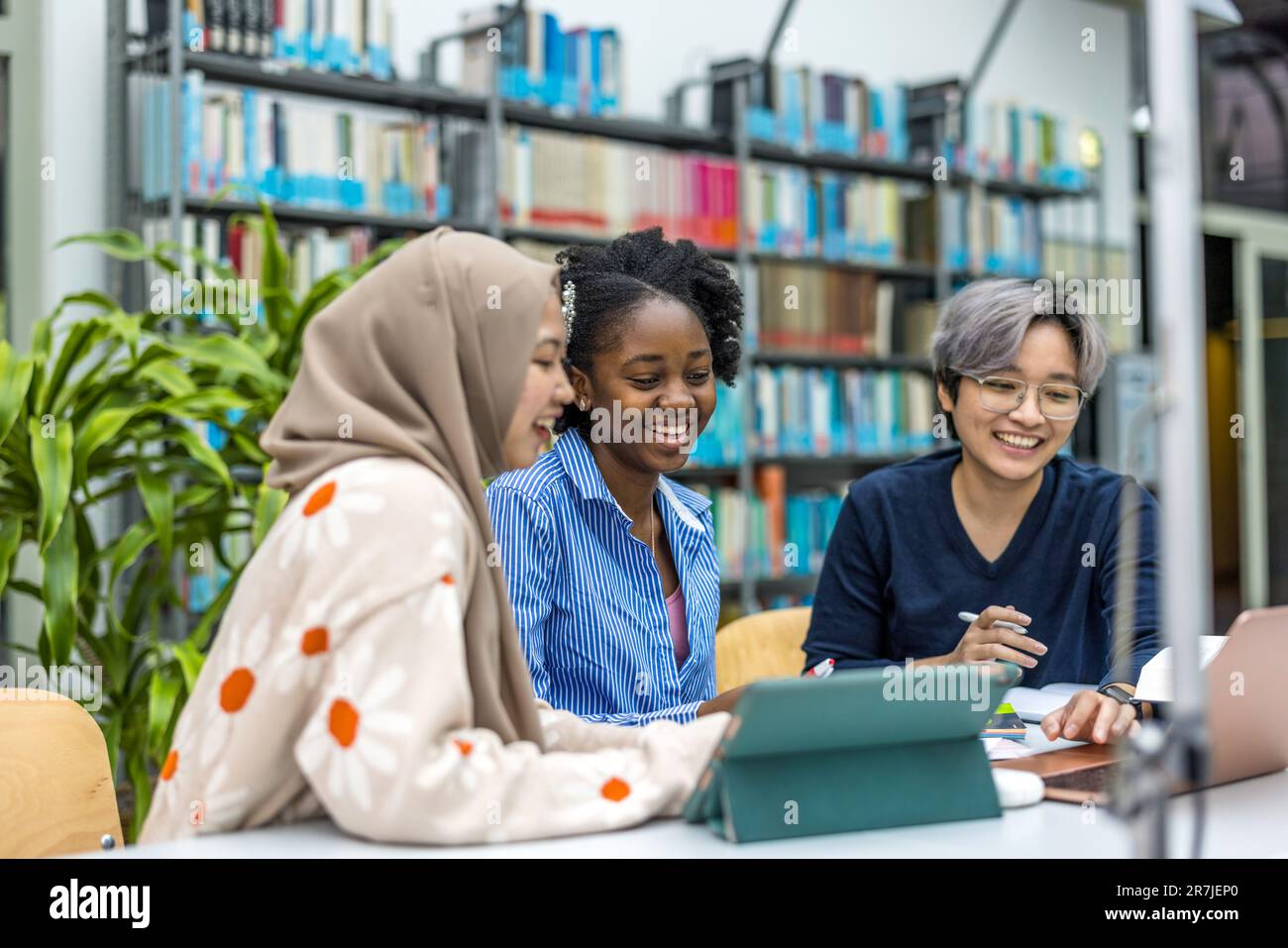 Multiethnic group of students sitting in a library and studying ...