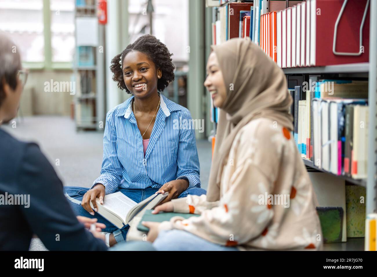 Multiethnic group of students sitting in a library and studying ...